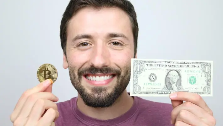 Man holding crypto coin and dollar bill