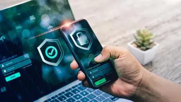 man looking at a laptop and a mobile, both of which show security locks on the screen  