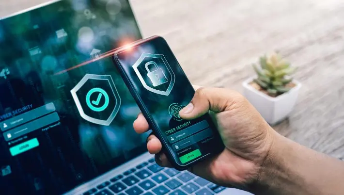 man looking at a laptop and a mobile, both of which show security locks on the screen  