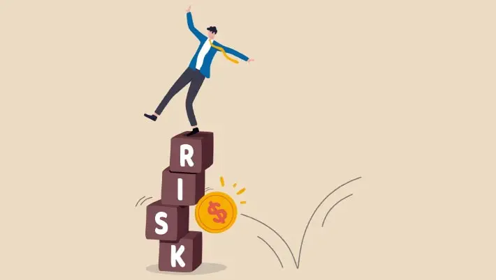 man balancing on blocks that spell out "risk" as a $ coin bounces by  