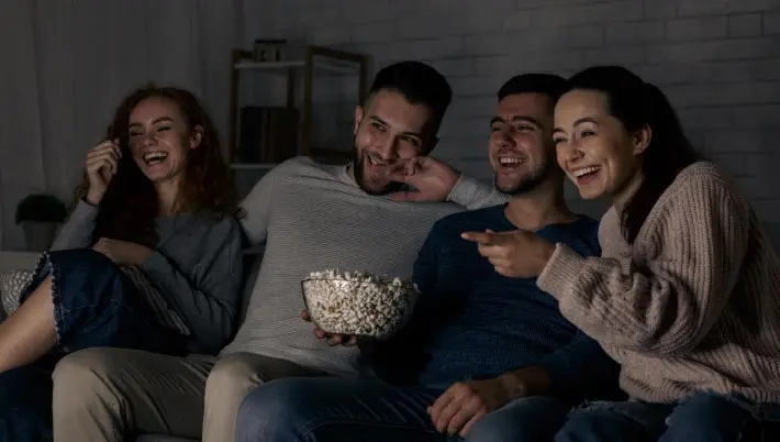 friends eating popcorn and looking at a gaming screen 