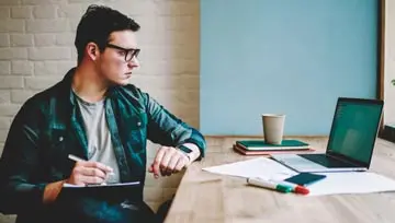 man writing down what he's seeing on the screen