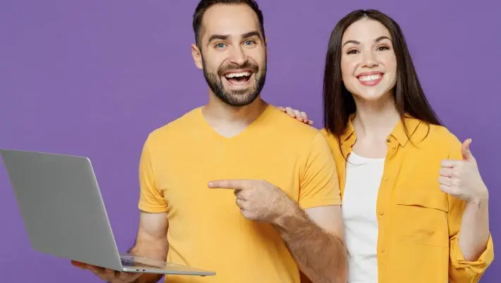 man and woman celebrating a win on their laptop