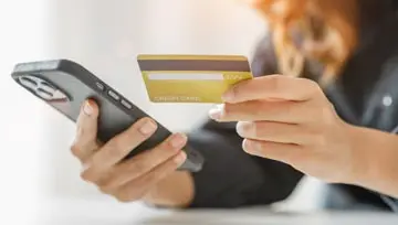 woman holding a credit card and a cell phone