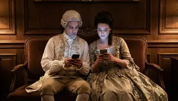 couple dressed in period clothes playing on mobile phones 