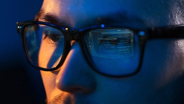 close up of the eyes of a man wearing glasses looking at a computer screen