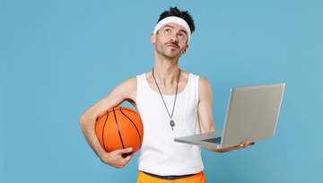 skinny guy wearing basketball clothes, holding a basketball and a laptop