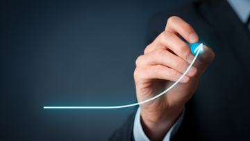 a man drawing an upward graph on a glass