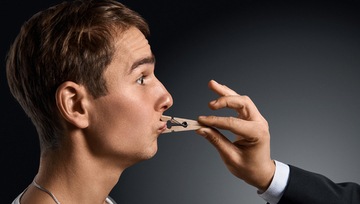 a young man with a clothes pin on his lips