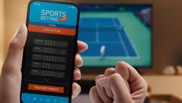 watching football game on a laptop screen and making a bet on a smartphone 