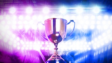 a winner's trophy on the background of a lit up stadium